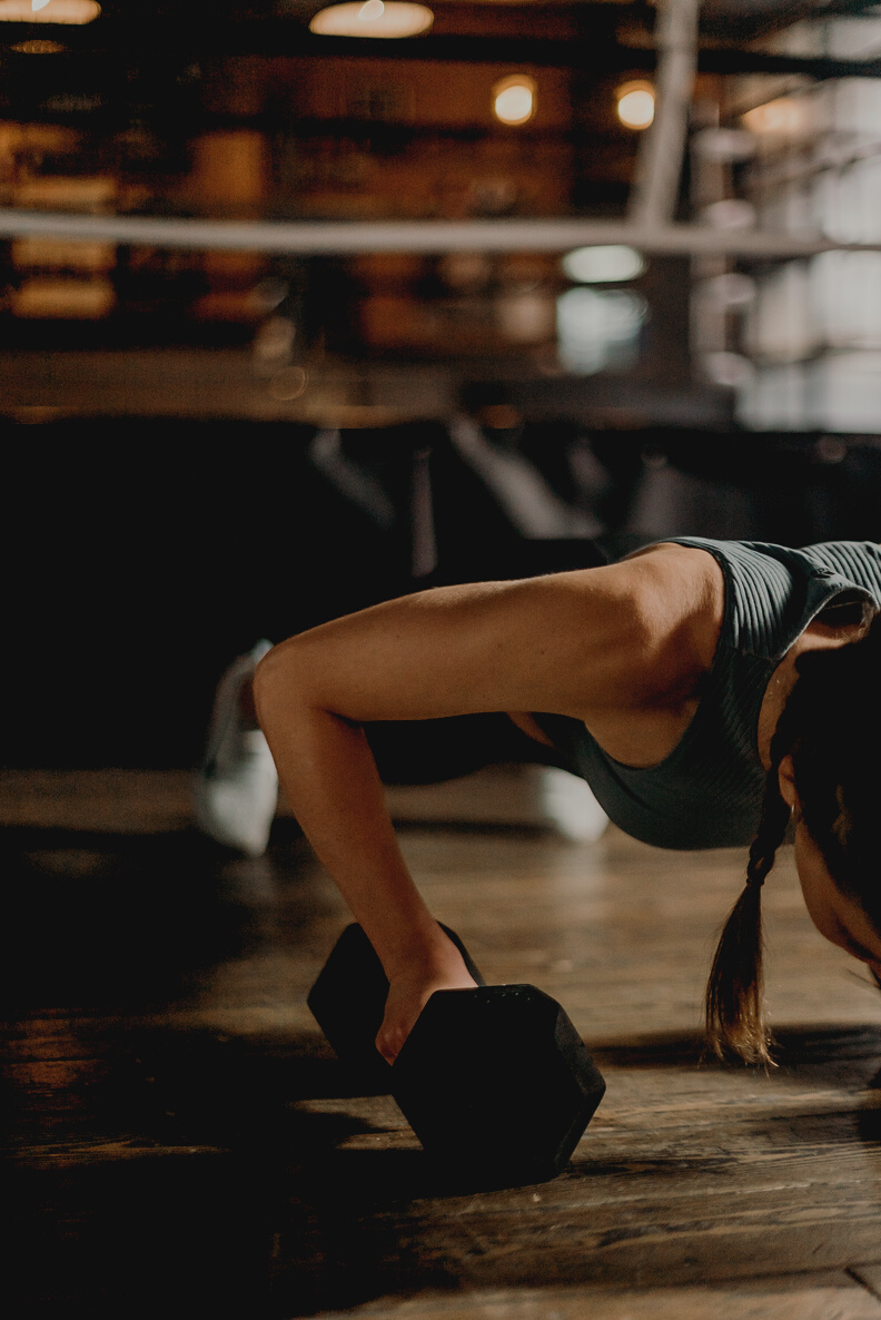 Woman in Black and White Tank Top and Black Shorts Lying on Brown Wooden Floor